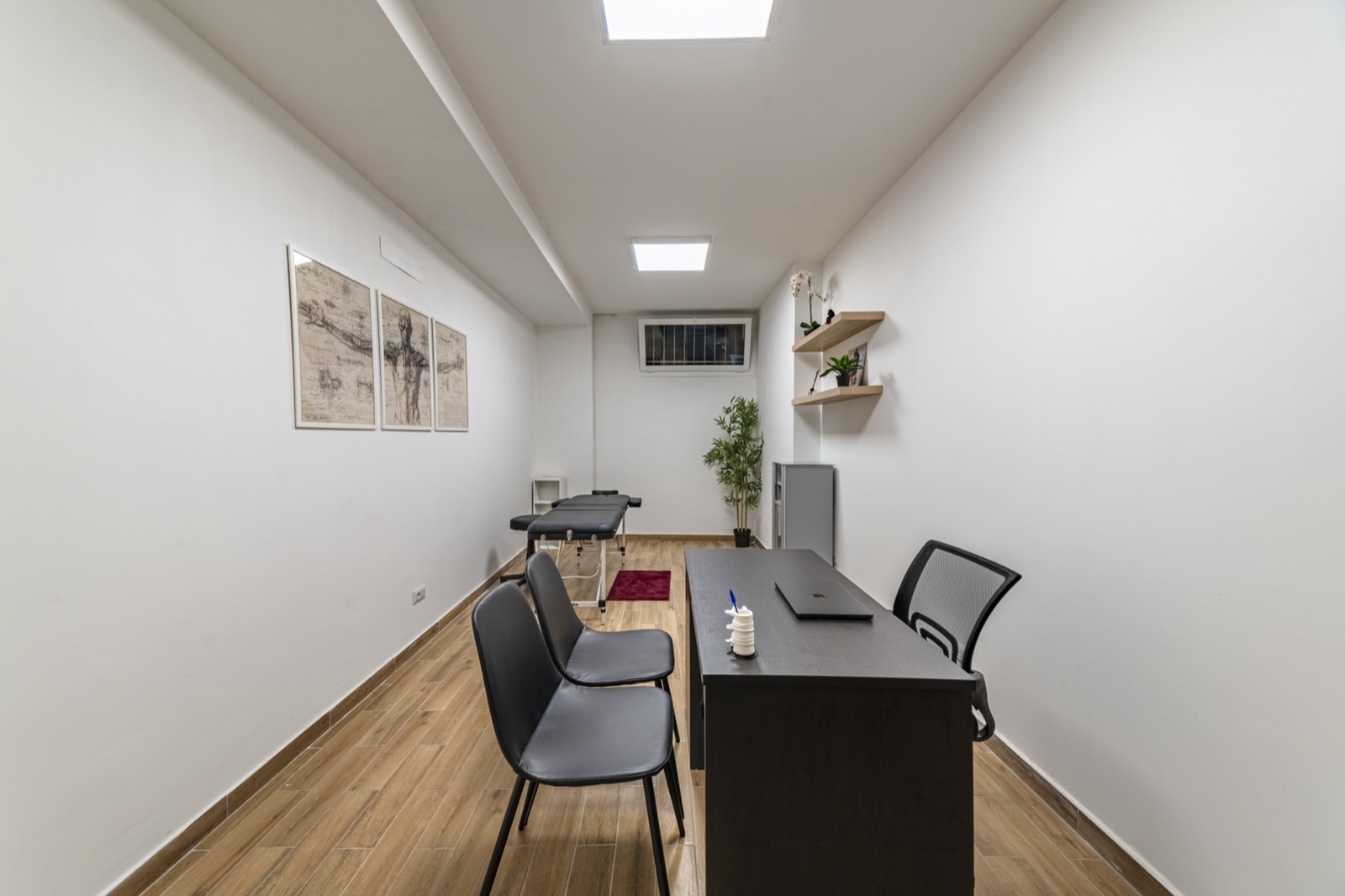 Vista dell’ambiente dall’ingresso, con scrivania e lettino sul fondo